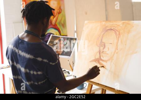 African american male painter at work painting portrait on canvas in art studio Stock Photo