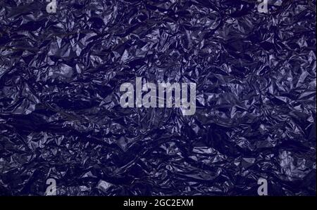 Crumpled cellophane blank dark blue plastic paper texture abstract background. Stock Photo