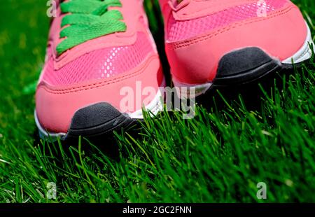 pink sports trainers on green grass background Stock Photo
