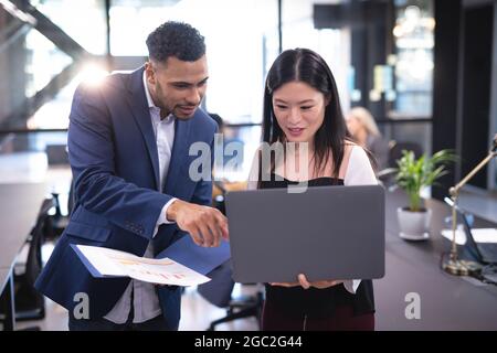 Two diverse male and female business colleagues using laptop and talking Stock Photo