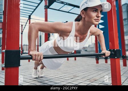 Sportswoman doing push-ups from a horizontal bar Stock Photo