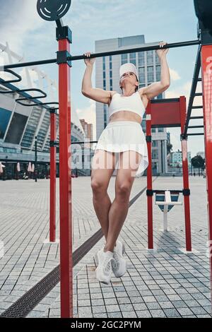 Female athlete doing chin-ups on pull-up bar Stock Photo