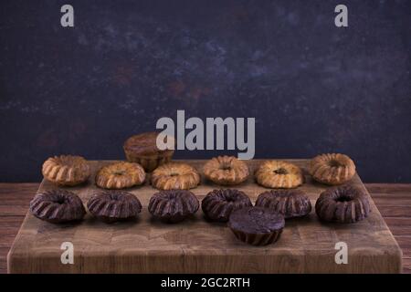 Milk and chocolate muffins on a wooden board in the form of a checkerboard on an abstract blue background with copy space Stock Photo