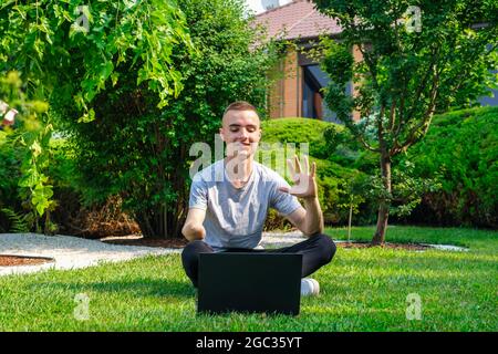 Guy with amputated arm sits on lawn and talking with friends via social network  Stock Photo