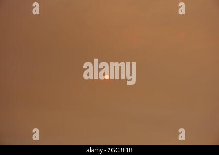 Sun shining through a cloud of smoke caused by forest fire Stock Photo