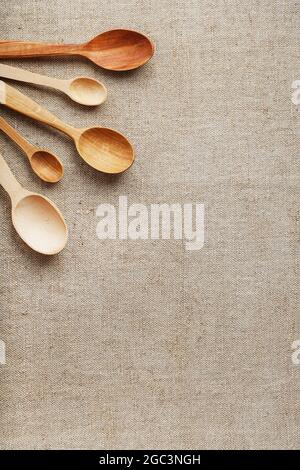 Natural wood spoons in a row on burlap fabric. Natural natural materials. Caring for the environment Stock Photo