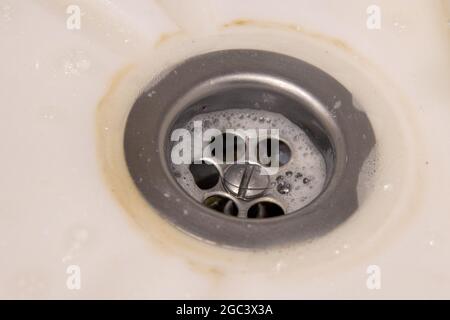 metal sink in a white bathtub, sink. Dirty drain. The concept of homework, disinfection. Stock Photo