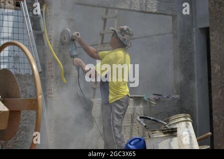 Bricklayer. Worker doing renovation of commercial area, cutting wall with hand equipment in building in internal view, with lamps and walls, in Brazil Stock Photo