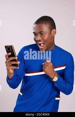excited and happy young black man viewing content on his phone rejoicing Stock Photo
