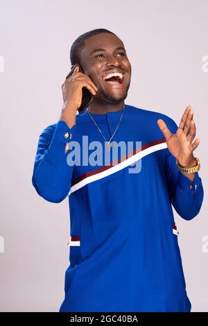 handsome young african man making a phone call, feeling excited and happy, making gestures with his hands Stock Photo