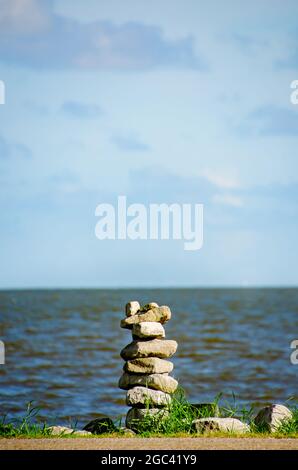 Rocks are stacked on the side of the road by Portersville Bay, July 13, 2021, in Coden, Alabama. Rock balancing or stone balancing is a hobby for some. Stock Photo