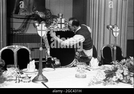 Behind the scenes at a state banquet. Homecoming banquet for Queen Elizabeth II at the Mansion House, London after her Commonwealth Tour in 1954. The catering firm of Ring & Brymer (Birch’s) Ltd have handled the catering at every Coronation banquet given by the Corporation of London since Queen Victoria’s Coronation and have catered for more crowned heads than any other firm in the world. 19 May 1954 Photo shows: The Queen’s Own Chair gets a good dust and brush-up Stock Photo