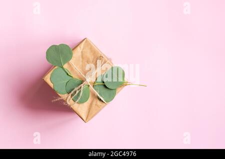 Gift box wrapped in brown paper decorated with eucalyptus branch, natural eco friendly zero waste gift wrapping idea. Top view. Copy space. Stock Photo