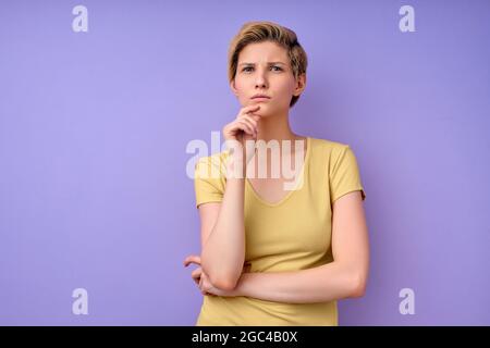 Closeup photo of amazing short hairdo lady looking at camera empty space deep thinking creative person arm on chin wearing casual yellow t-shirt isola Stock Photo