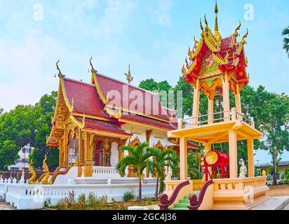 The viharn hall with gable (pyathat) roof and the Ho Rakang bell tower with a ritual gong, Wat Sangkharam Temple, Lamphun, Thailand Stock Photo