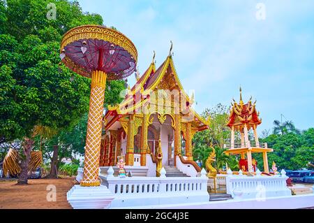 The scenic chatra ceremonial umbrella, viharn hall and a bell tower of Wat Sangkharam Temple (Pratu Lee), Lamphun, Thailand Stock Photo