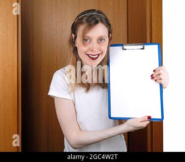 Young female apprentice working in marketing industry holding empty white paper on clipboard Stock Photo