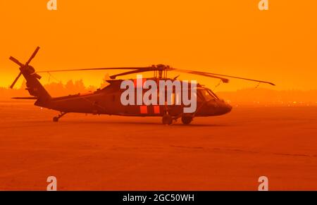 An Army National Guard UH-60M Black Hawk  helicopter waits on the tarmac in heavy smoke at the Aurora State Airport, near Aurora, Ore. on September 9, 2020. Flight crews from the Oregon Army National Guard’s Gulf Company, 1st Battalion, 189th Aviation Regiment based out of Salem, Ore. were called in to support state and local officials as unprecedented fire conditions forced evacuations across the state. Guard helicopters have dropped more than 22,000 gallons of water on Oregon's wildland fires since mid-August. (National Guard photo by Maj. Leslie Reed) Stock Photo