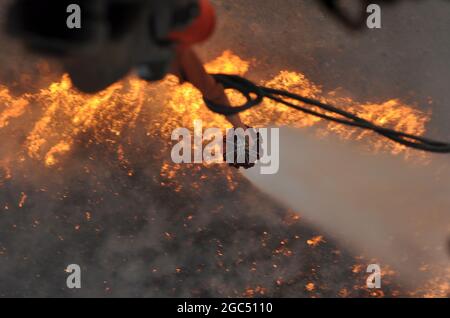 An Oregon Army Guard HH-60M Black Hawk helicopter empties a water bucket onto flames on the Brattain Fire on September 15, 2020 near Paisley, Ore. Two Oregon Guard Black Hawks, headquartered out of Salem, Ore. are currently assigned to the fire. The helicopters concentrated on dumping water buckets on the north perimeter of the fire in coordination with other aircraft supporting wildland firefighting efforts. (National Guard photo by Maj. Leslie Reed, Oregon Military Department Public Affairs). Stock Photo