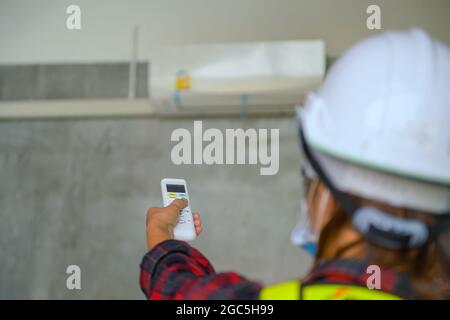 A young Asian air conditioner technician or air-conditioning installation technician is about to repair air conditioning in homes and buildings.Air co Stock Photo