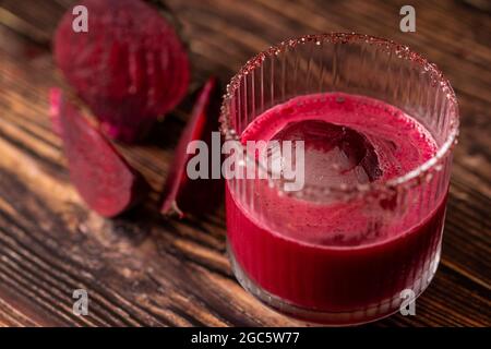 Alcoholic beetroot cocktail beverage in elegant glass on wooden table. Stock Photo