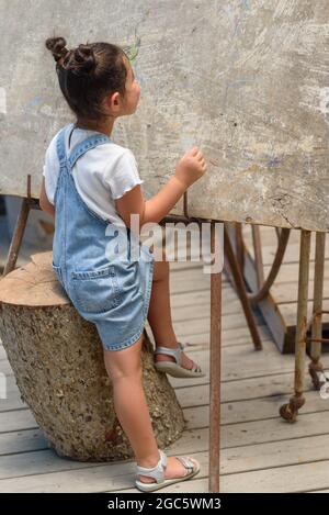 Beautiful little girl writing on classroom board. Camp, outdoor class room in nature. Stock Photo