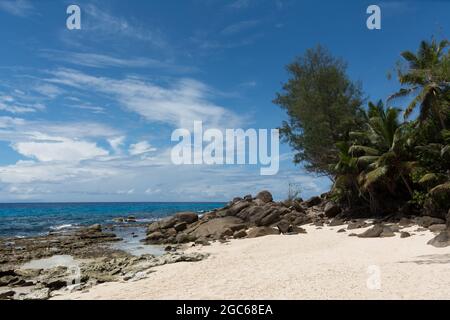 Beautiful beach with rocks in the foreground and turquoise blue waters at daytime at Police Bay in Mahe, Seychelles Stock Photo