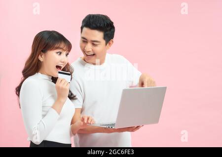 Excited young couple shopping online, holding credit card and looking at laptop Stock Photo