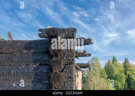 Burnt old log house in the village on a bright summer day against the blue sky. Close-up Stock Photo