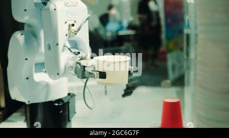 Robot with artificial intelligence making coffee on coffee machine. Close up shot Stock Photo