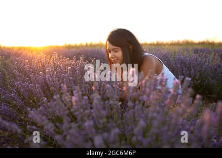 young latin woman enjoys nature amidst lavender flowers at sunset Stock Photo
