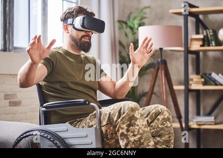 Disabled ex-serviceman in a wheelchair using a VR headset Stock Photo