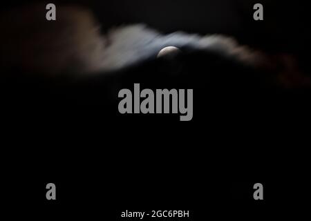 September Harvest Moon partially obscured by dark clouds Stock Photo