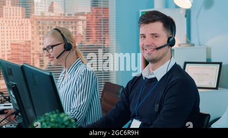 Handsome man service operator talking to the client on phone in call center. He using headset helping people. Stock Photo