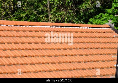 house with double pitched roof in tiles, evident the ridge line and sheaths under ridge tiles. Stock Photo