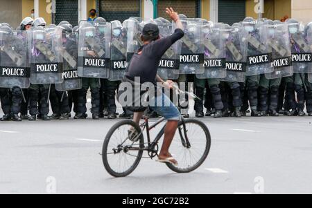 Bangkok, Thailand. 07th Aug, 2021. A protester rides a bicycle in front of riot policemen during the demonstration. The Metropolitan Police Bureau (MPB) will deploy at least 5,700 officers to ensure public order and security during the anti-government rally in the capital. The Free Youth group will gather at Democracy Monument on Ratchadamnoen Avenue before they march to the Grand Palace. (Photo by Chaiwat Subprasom/SOPA Images/Sipa USA) Credit: Sipa USA/Alamy Live News Stock Photo