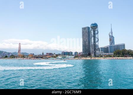 Batumi, Georgia - July 2, 2021: Batumi coastline. Popular Georgian resort city at Black Sea. Panoramic view of Ferris wheel, alphabetic tower, skyscrapers and the beach from the sea. Stock Photo