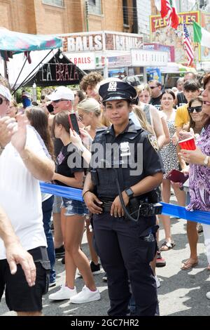 Female NYPD police officer on the job at the annual Giglio feast  and festival in North Williamsburg, Brooklyn which draws thousands of people every year. People of all ethnicities crowd North 8th Street at the  annual Italian Giglio Feast in Williamsburg, Brooklyn, NYC. Stock Photo