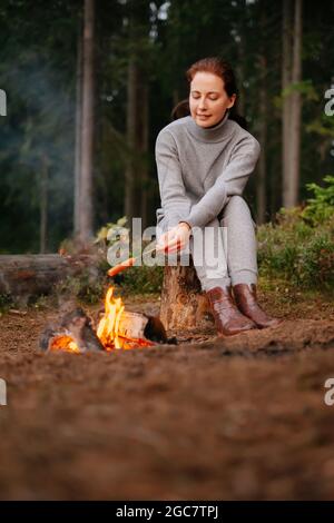 Young woman cooks sausages on a campfire Stock Photo