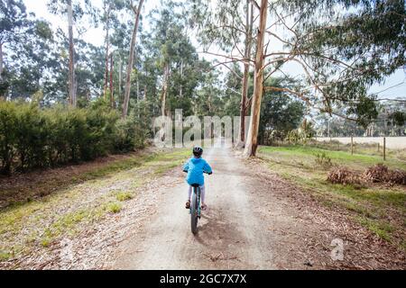 A child cycles at speed in Mt Evelyn on the popular Lilydale to Warburton Rail Trail on a warm autumn day in Victoria, Australia Stock Photo