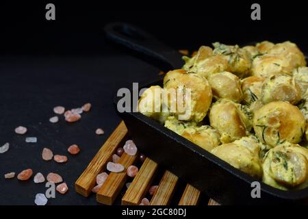 Champignons in sour cream. Cast iron pan with fried mushrooms on a black background. Close-up Stock Photo