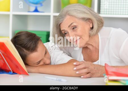 Grandmother with sleeping grandson after doing homework at home Stock Photo