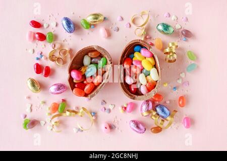 Chocolate Easter eggs and other sweets on pink background. Party dessert Stock Photo