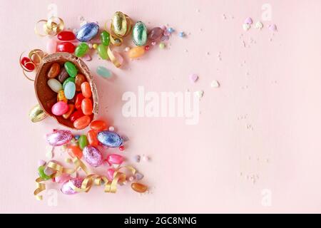Chocolate Easter eggs and other sweets on pink background. Party dessert Stock Photo