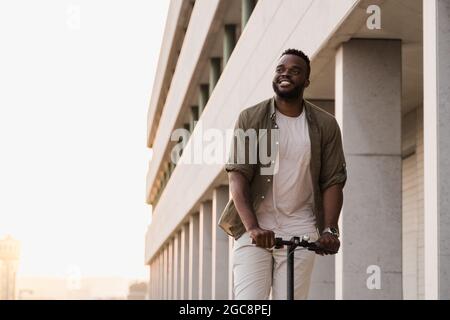 Young african american man using electric scooter outdoor in the city - Focus on face Stock Photo