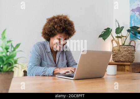 Happy african mature woman using laptop computer at home office - Focus in face Stock Photo