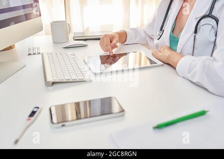 An unrecognizable female doctor uses her digital tablet Stock Photo