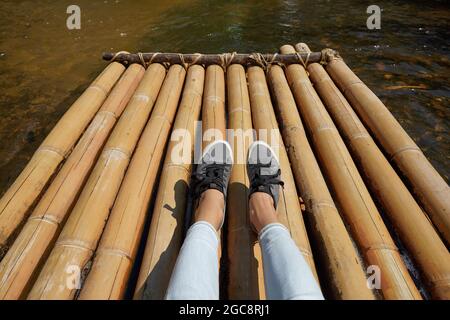 Woman sitting on the bamboo raft floating in clear water Stock Photo