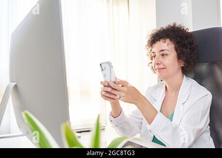 A female doctor using her smartphone at her workplace Stock Photo