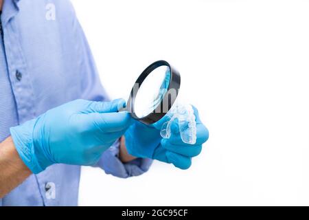 Dentist in blue shirt and white background examining a dental splint ...